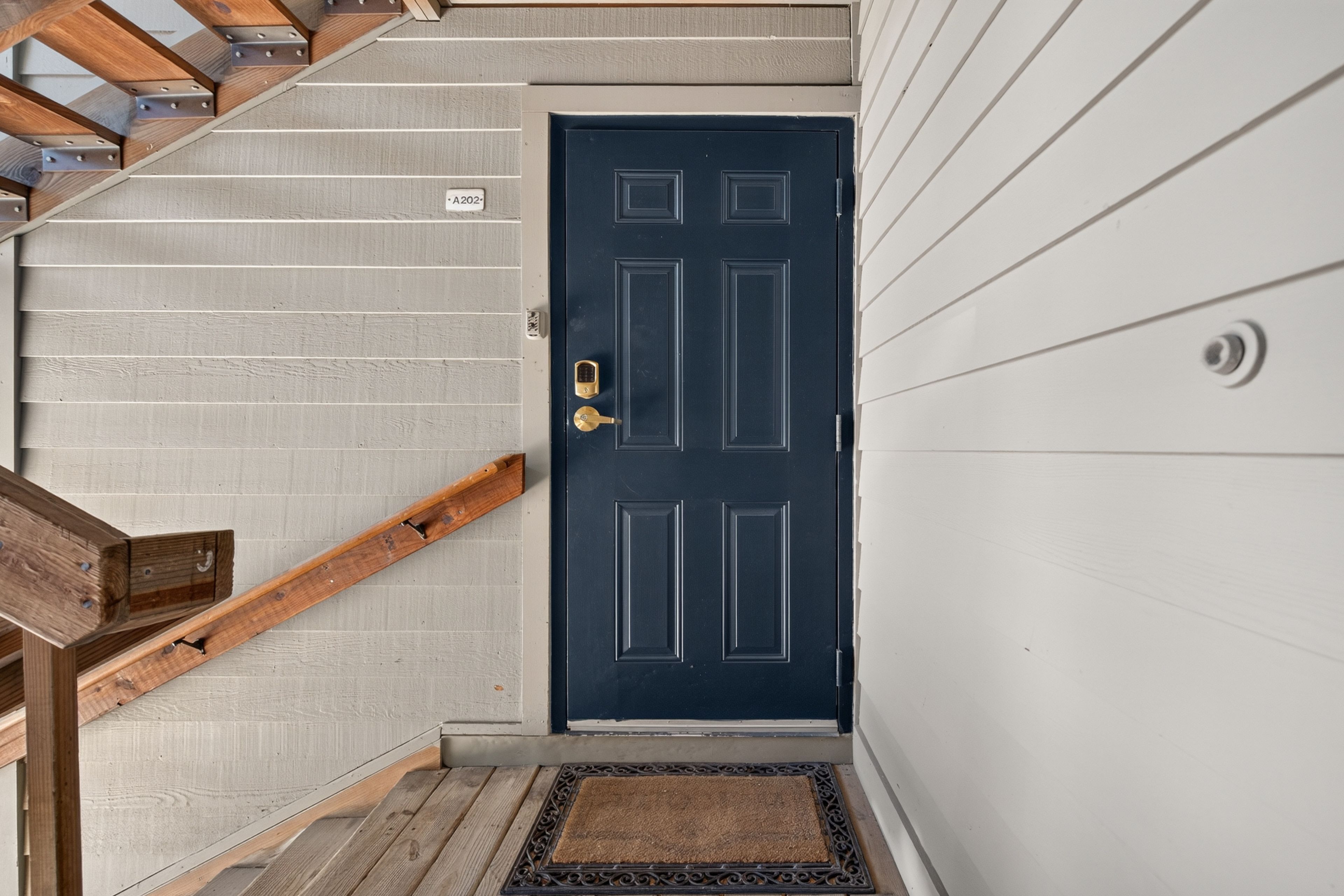 A staircase leading to a dark blue door with a keyhole and a doormat at the bottom.