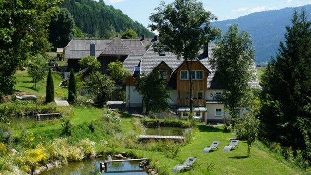 A lakeside property with a small pond, wooden deck, and lounge chairs. - Apartment With 1 Bedroom (Sankt Georgen am Kreischberg)