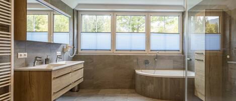 Un baño moderno con una bañera independiente, un lavamanos doble y una cabina de ducha con paredes de vidrio.
