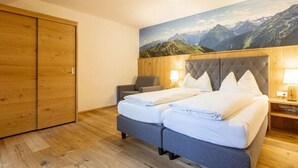 A hotel room with a double bed, a wooden wardrobe, a chair, and a mountain landscape mural on the wall. - Apartment With 1 Bedroom (Sankt Georgen am Kreischberg)