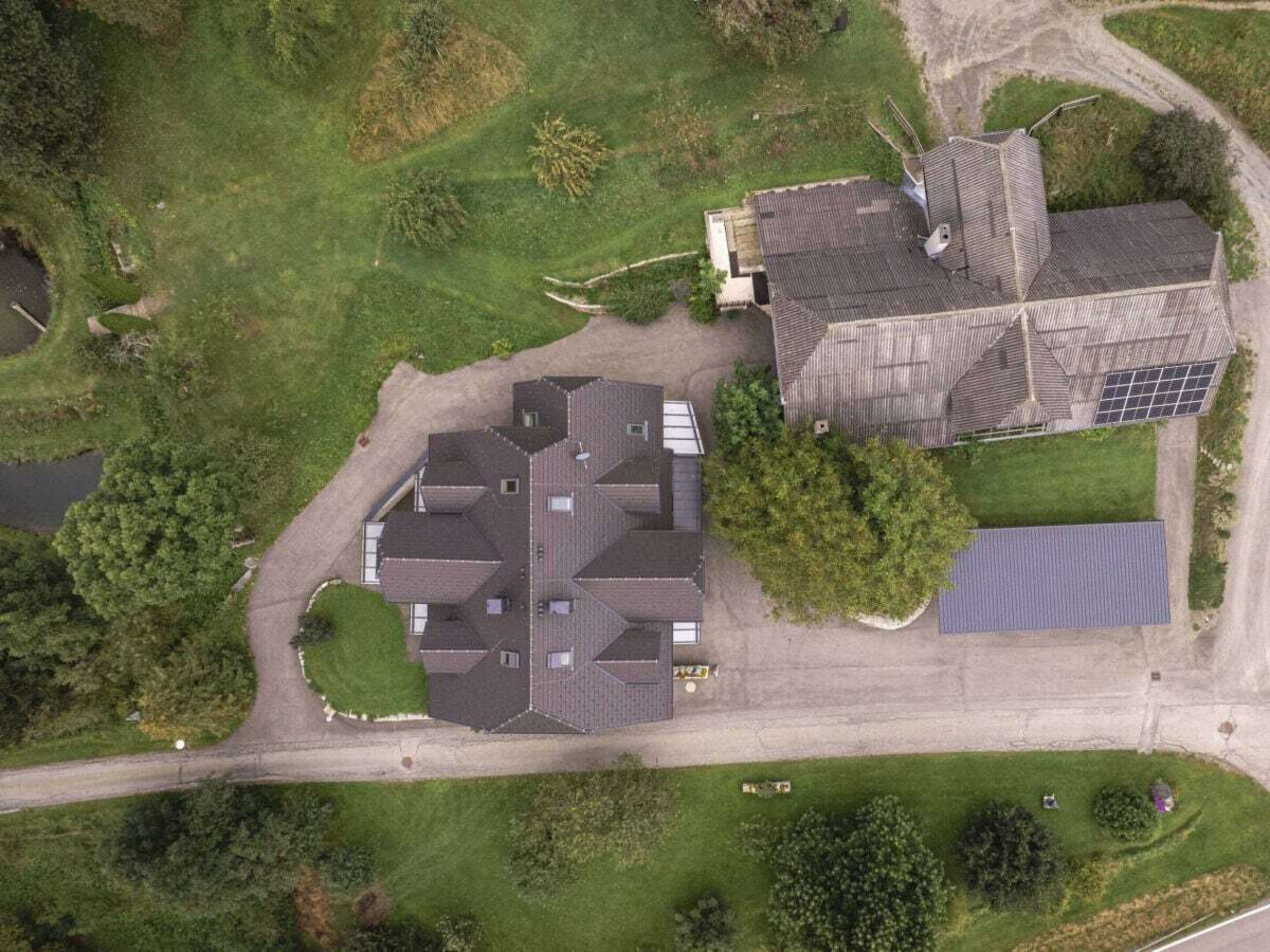 Vista aérea de una propiedad residencial con una casa grande, un garaje y un conjunto de paneles solares.