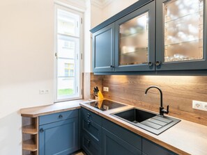 Eine Küche mit blauen Schränken, einer Holz Arbeitsplatte, einem Spülbecken und einem Fenster.