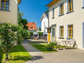 Ein Innenhof mit einem Weg, Sitzgelegenheiten im Freien und einem kleinen Baum.