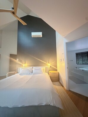 A modern bedroom with a bed, bedside lamps, a ceiling fan, and a wall-mounted air conditioning unit. - Luxury 5 bed home, spa, games room, pool, slide, firepit, nearby hikes, (Samford Valley)