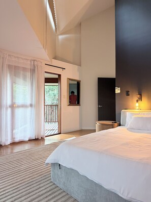 A modern hotel room with a large bed, a small bedside table, a mirror, and a balcony with a view. - Luxury 5 bed home, spa, games room, pool, slide, firepit, nearby hikes, (Samford Valley)