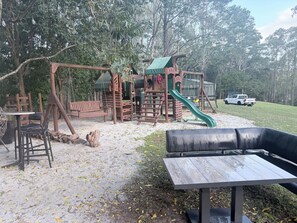 A playground with a slide and swings, a bench, and a picnic table. - Luxury 5 bed home, spa, games room, pool, slide, firepit, nearby hikes, (Samford Valley)