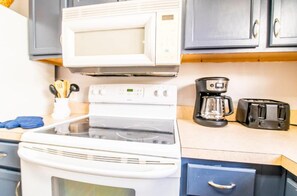 Cozinha equipada com fogão, micro-ondas, cafeteira e torradeira.