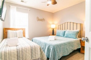 A bedroom with two beds, a ceiling fan, a wall-mounted lamp, and a 'Beach' sign. - 301 Chester Street: 2  BR, 2  BA Condominium in Myrtle Beach, Sleeps 7 (Myrtle Beach)