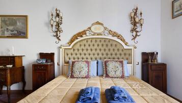 Ein Schlafzimmer mit einem großen Bett, zwei Nachttischen, einer Kommode und einem Gemälde an der Wand.