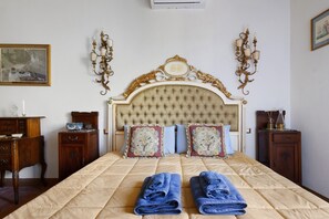 Ein Schlafzimmer mit einem großen Bett, zwei Nachttischen, einer Kommode und einem Gemälde an der Wand.