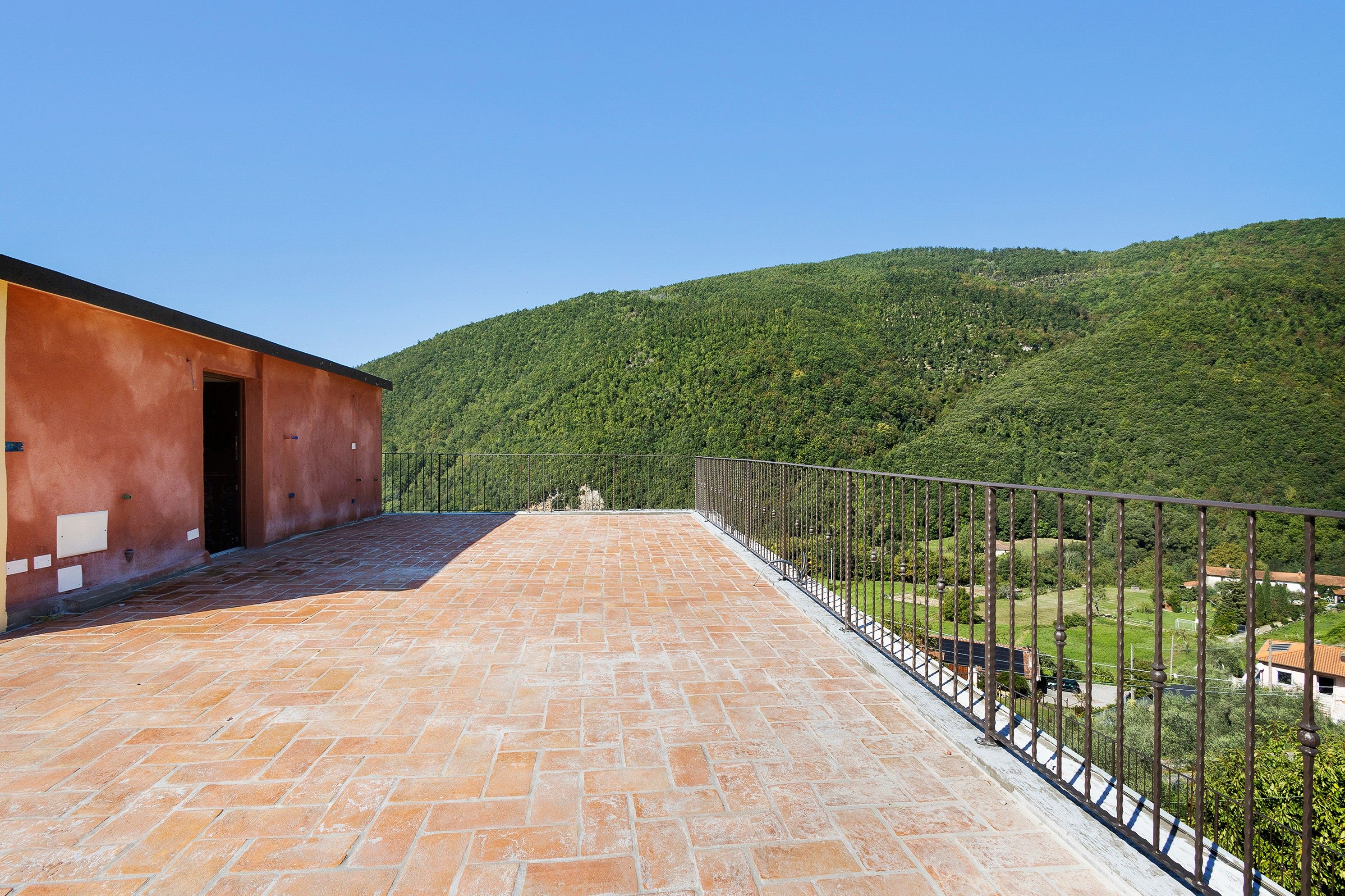 A balcony with a view of a forested hillside.