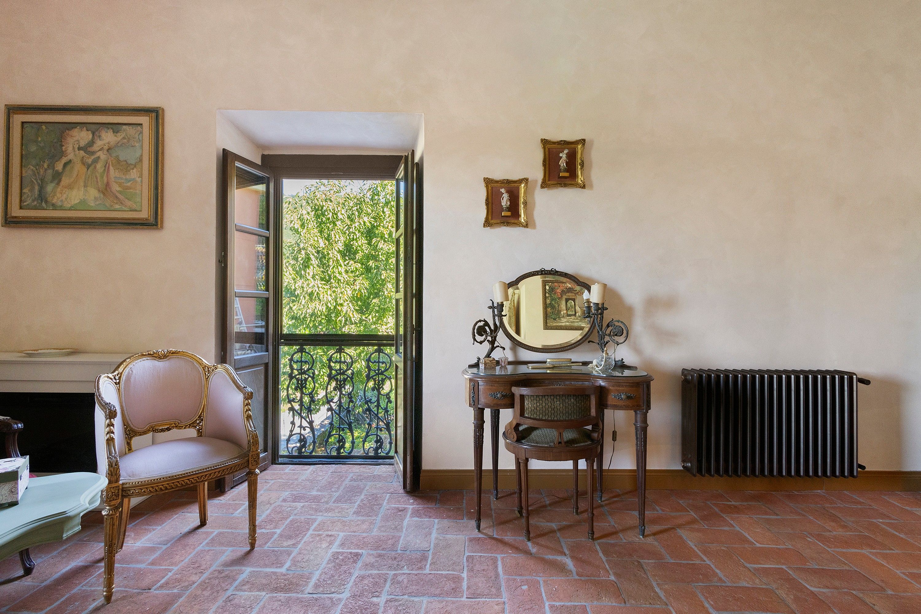 Une pièce comprenant une chaise, une commode avec un miroir, un radiateur et une fenêtre donnant sur un espace verdoyant.