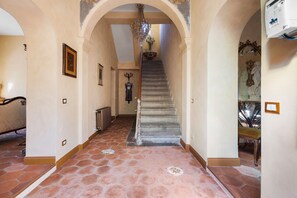 Un passadís majestuós amb una escala, detalls ornamentals a les parets i un penjallum.