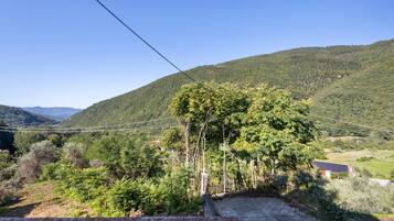 Paesaggio rurale con una collina, alberi e una costruzione in mattoni.