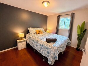 Een slaapkamer met een bed, nachtlampjes, een raam met gordijnen en een potplant.