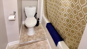 A bathroom with a toilet, a shower curtain with a geometric pattern, and a blue towel. - Your private terrace next to St Boniface Université and Hospital Ver Walkable (Winnipeg)
