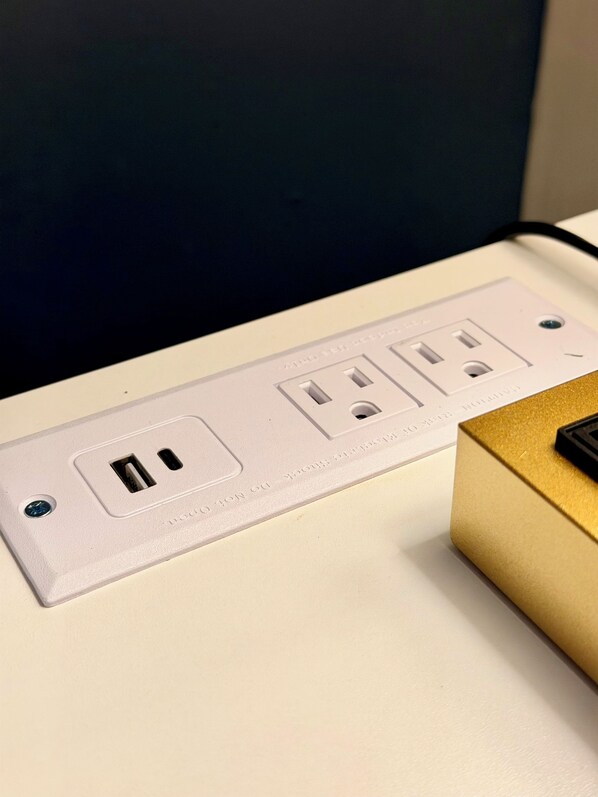 Een witte elektrische stekkerdoos met vier stopcontacten, een USB-poort en een aardingsschroef.