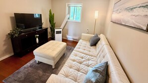 A living room with a flat-screen TV, a sofa, a coffee table, a potted plant, and a painting on the wall. - Your private terrace next to St Boniface Université and Hospital Ver Walkable (Winnipeg)