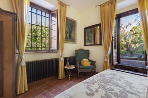 Ein Zimmer mit einem Bett, einem Sessel, einer Heizung und einem Fenster mit Vorhängen.