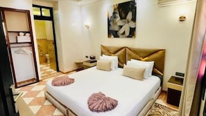 Quarto de hotel com cama grande, cabeceira, mesa de cabeceira e obra de arte pendurada na parede.
