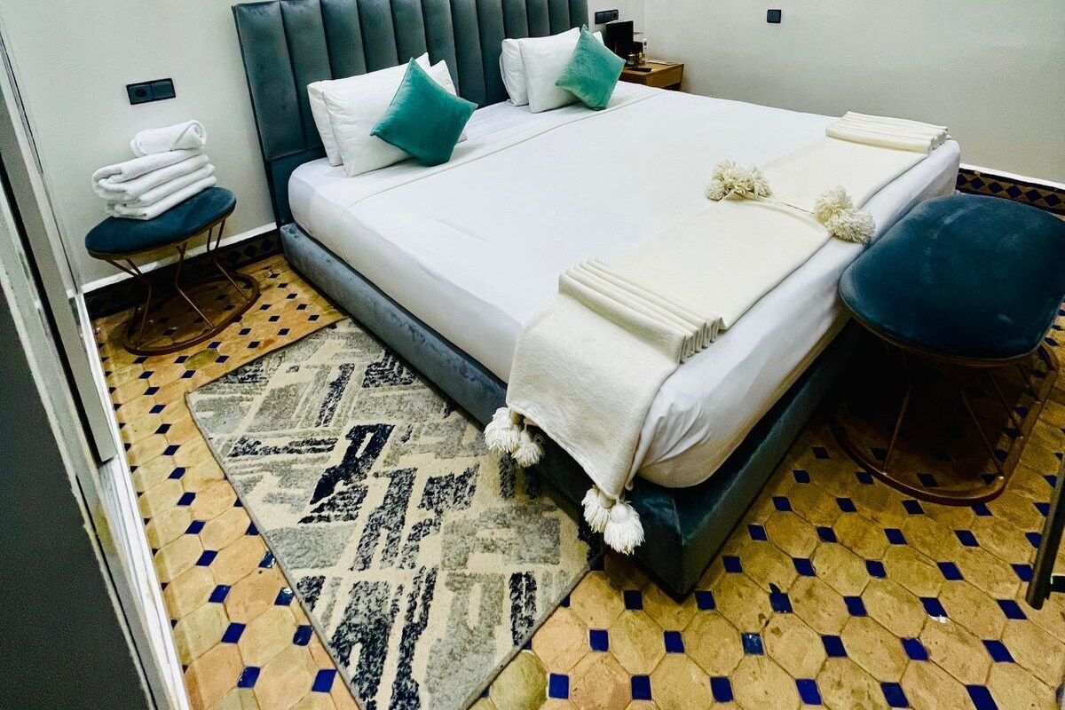 Un dormitorio moderno con una cama grande, un cabecero, una mesita de noche, un teléfono en la pared y una alfombra estampada.