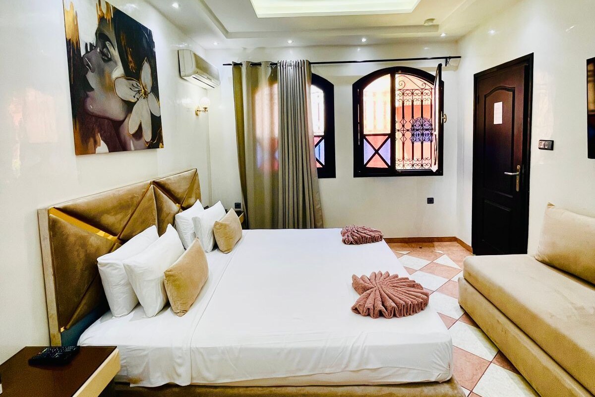 Habitación de hotel con una cama grande, un sofá, un tapete estampado y un cuadro en la pared.
