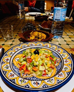 Una mesa con un plato colorido de ensalada, un tazón de comida y una botella de agua.