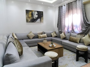 A modern living room with a grey sectional sofa, a wooden coffee table, and a painting on the wall.