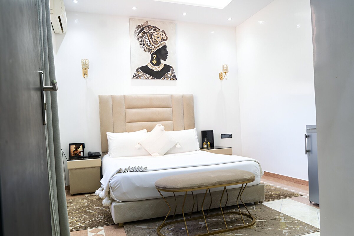 Un dormitorio moderno con una cama grande, una mesita de noche, una lámpara de pared y un cuadro.