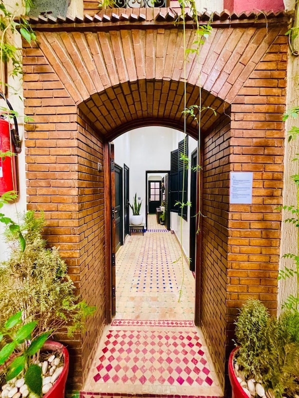 A narrow brick corridor with a tiled floor leading to a door. - Riad Douirtna (Marrakech)