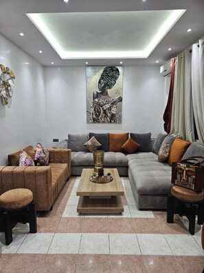 A modern living room with a sectional sofa, a coffee table, and a wall-mounted artwork. - Riad Douirtna (Marrakech)