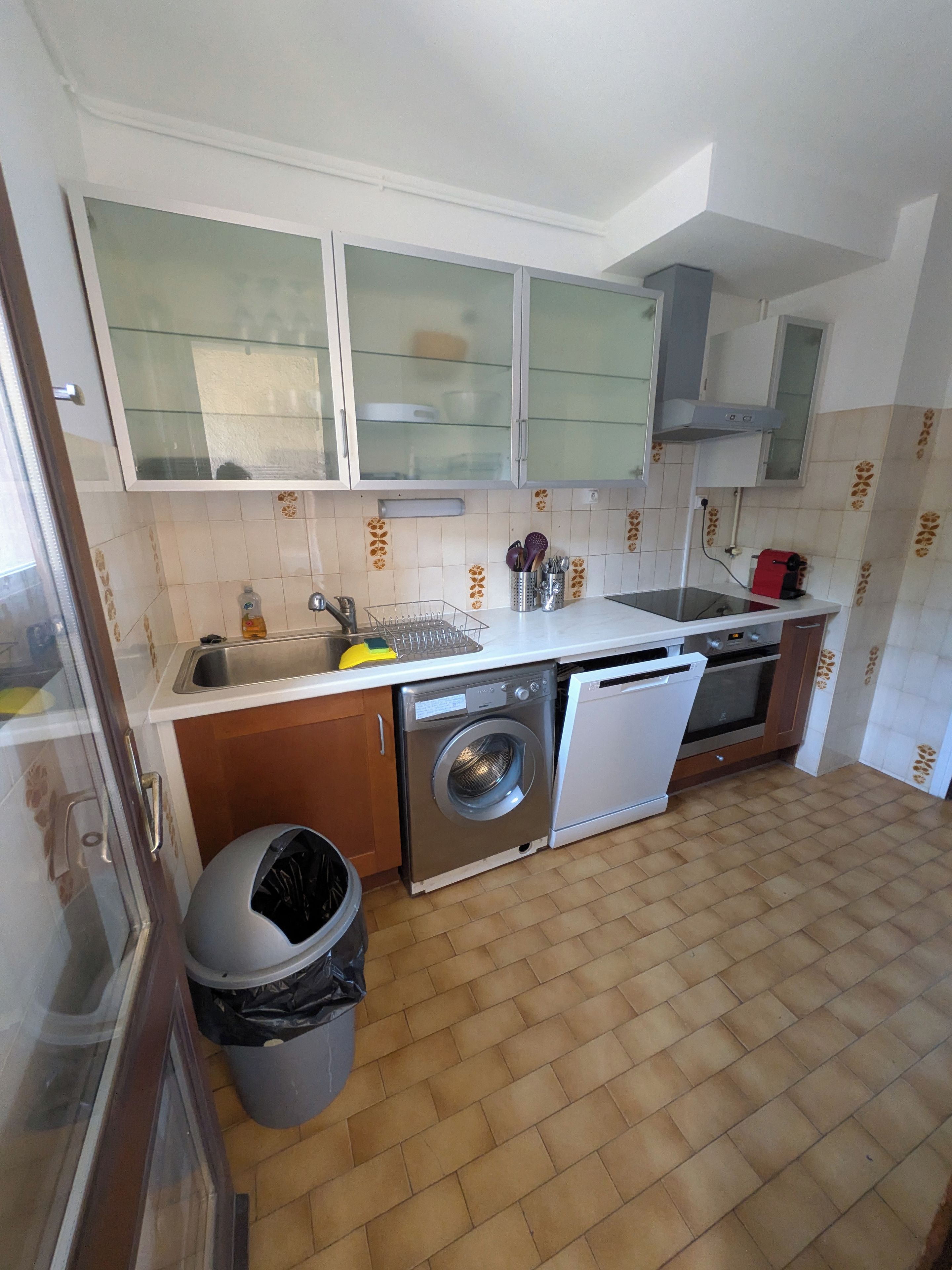 Cocina compacta con lavadora, lavavajillas y una pequeña zona de fregadero.