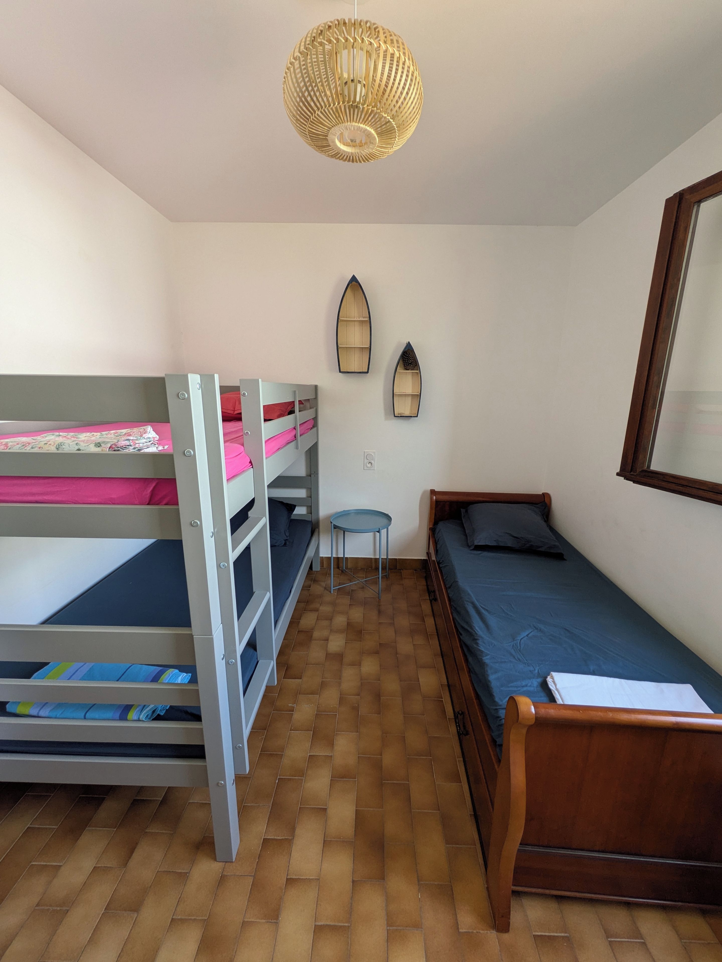 A dormitory room with bunk beds, a small table, and a single bed.