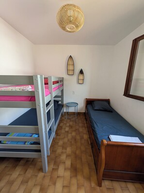 Um dormitório com beliches, uma mesa pequena e uma cama de solteiro.