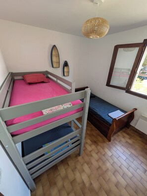 A bunk bed with a pink mattress, a wooden headboard, and a window with a view of the outside. - Family-friendly apartment right on the water (Argelès-sur-Mer)