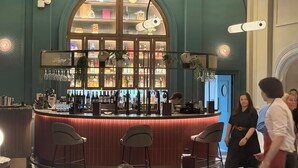 A bar area with a curved counter, bar stools, and a variety of bottles and glasses.