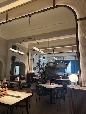 A restaurant interior with high ceilings, hanging pendant lights, and a view of the street through large windows. - Yellow B&B (York)