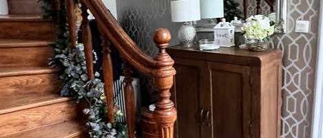 A wooden staircase with a spiral design, flanked by a decorative garland.
