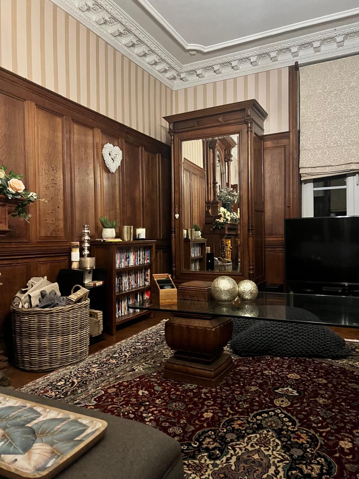 A traditional living room with a fireplace, bookshelves, a television, and a large mirror.
