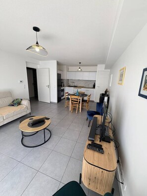 A modern living room with a sofa, a coffee table, and a dining area with chairs. - 49-square-meter apartment, 1 bedroom, terrace, and parking space (Aix-les-Bains)