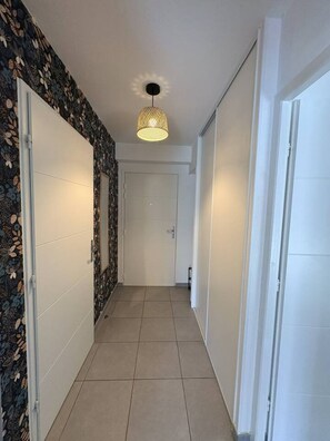 A hallway with patterned wallpaper, a tiled floor, and a door at the end. - 49-square-meter apartment, 1 bedroom, terrace, and parking space (Aix-les-Bains)