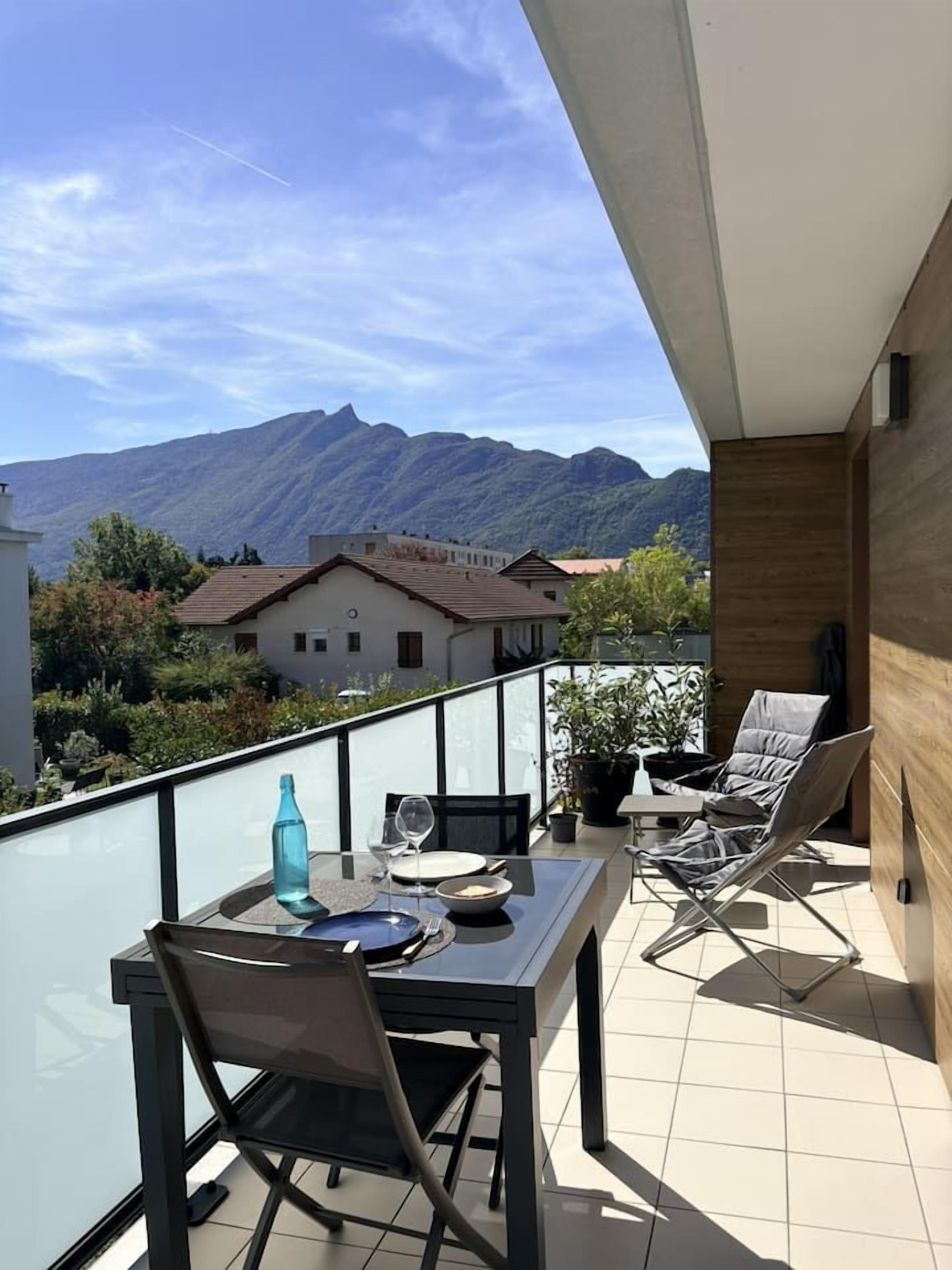 Ein Balkon mit Tisch, Stühlen, einer Flasche und einem Glas.