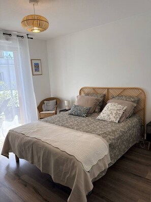A bedroom with a bed, a chair, a bedside table, a lamp, and a hanging light fixture. - 49-square-meter apartment, 1 bedroom, terrace, and parking space (Aix-les-Bains)