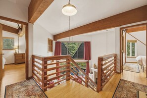 Ein geräumiger Lofts mit Holzbalken, einer Holztreppe und Blick auf Grünfläche.
