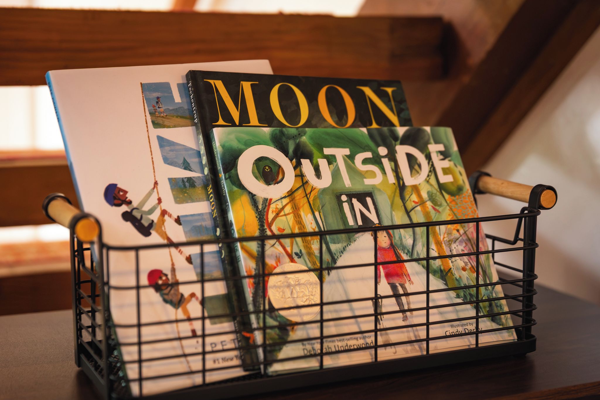 Un mueble para libros con dos libros titulados 'Moon Outside in' y 'Moon' sobre una superficie de madera.