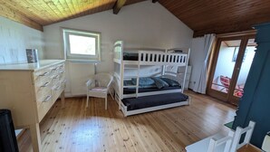 Una habitación con literas, un escritorio con cajones, una silla y un radiador.
