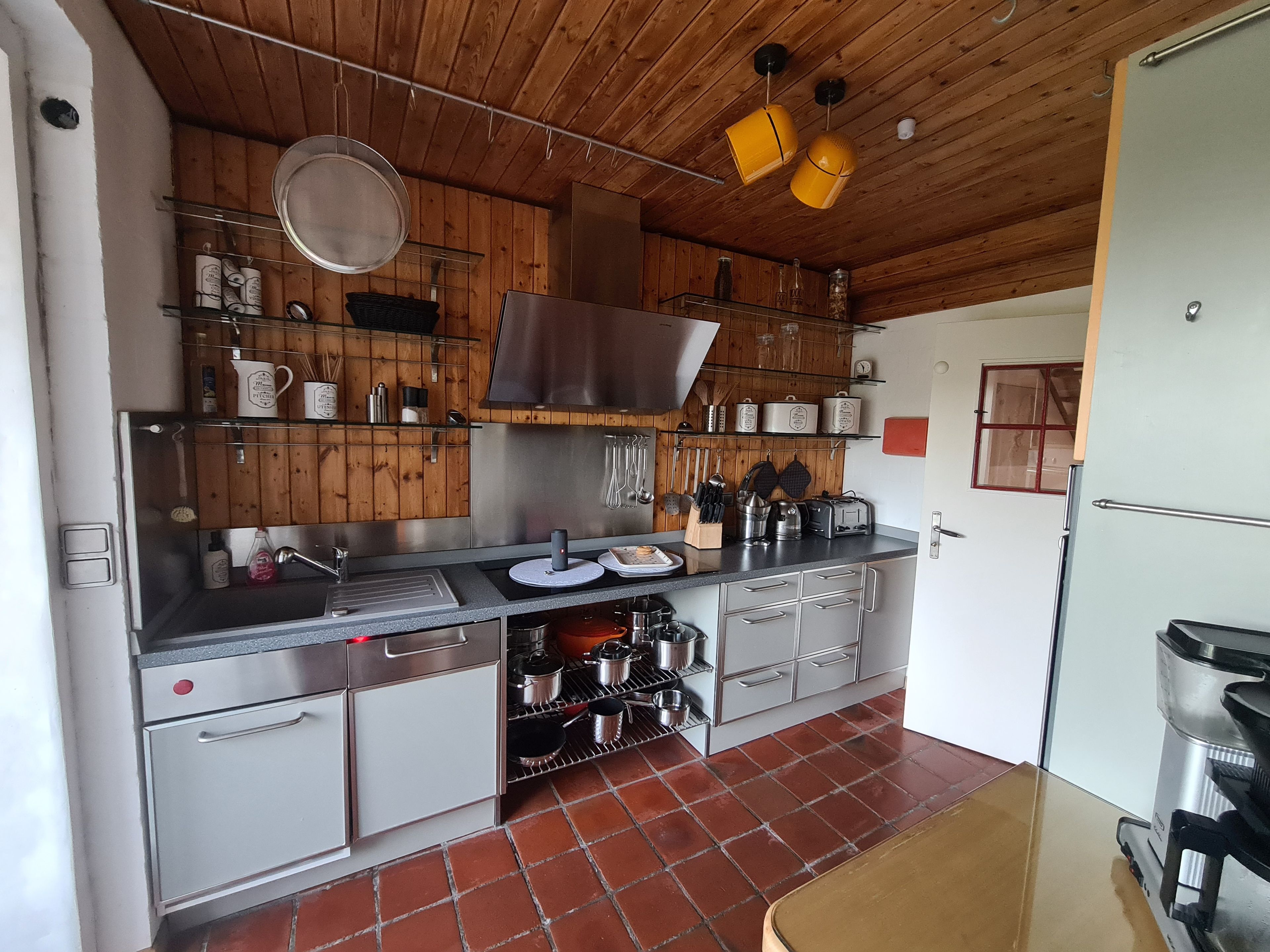 Eine Küche mit Holzschränken, Edelstahlgeräten und einem gefliesten Boden.