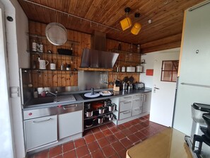 A kitchen with wooden cabinets, stainless steel appliances, and a tiled floor. - Familienglück - Die "AusZeit" vom Alltag (Schönberg)