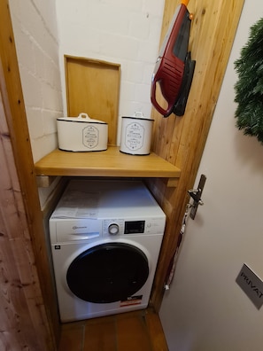 A laundry area with a washing machine, two white enamel containers labeled 'Paris Maison de Famille,' and a red tool hanging on the wall. - Familienglück - Die "AusZeit" vom Alltag (Schönberg)