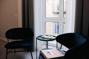 A room with a window, two chairs, a small table with cups, and a box with a flag design. - Six Luxury Rooms Quartieri Spagnoli (Naples)